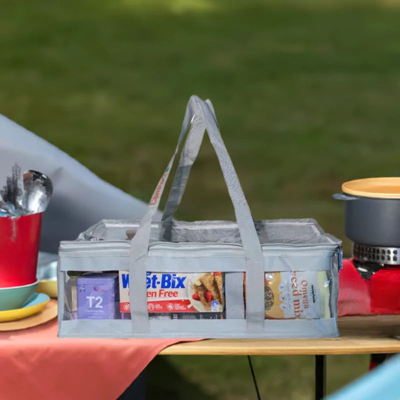 Grey clear under bed storage bag packed with pantry items sitting on picnic table