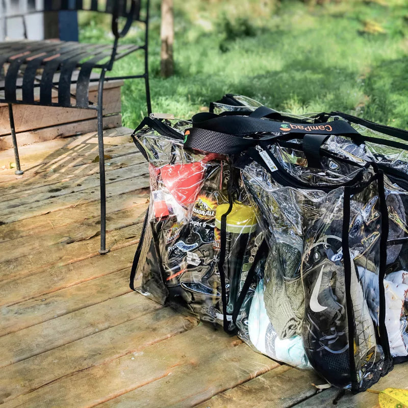 Large black trim clear camping bag filled with camping gear sitting on timber floor of deck