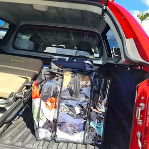 Large black trim clear camping bag packed with shoes and clothing sitting in back of 4WD